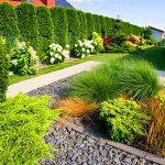 Seasonal Splendor: Year-Round Garden Beauty | The frontyard of a modern house, garden details with colorful plants, dry grass beds surrounded by grey rocks.