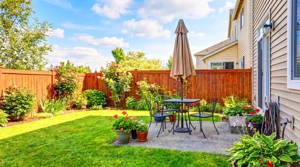 Landscaped residential backyard with patio furniture and wooden privacy fence