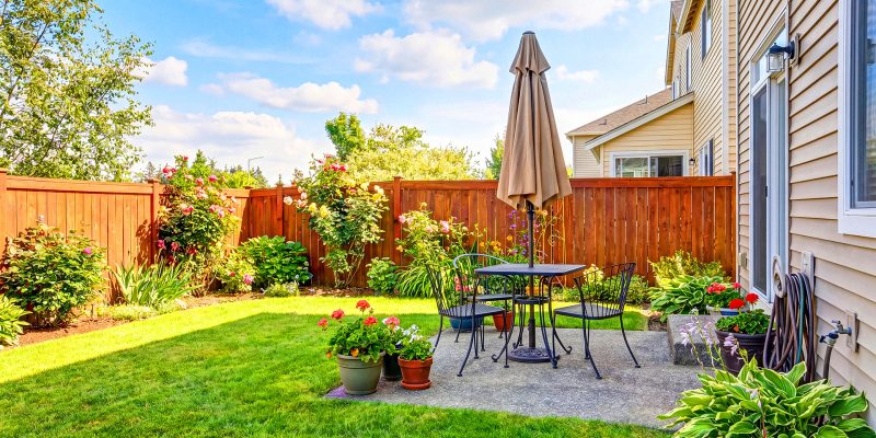 Landscaped residential backyard with patio furniture and wooden privacy fence