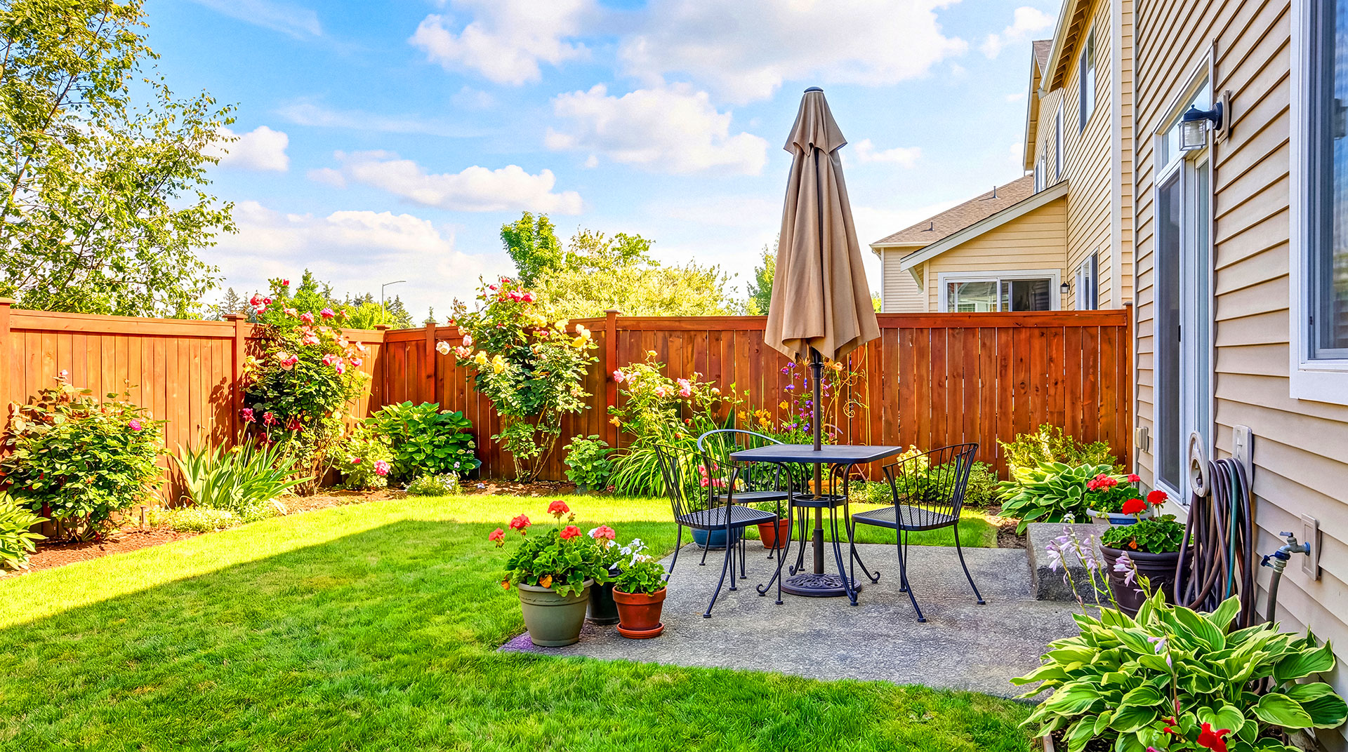 Landscaped residential backyard with patio furniture and wooden privacy fence