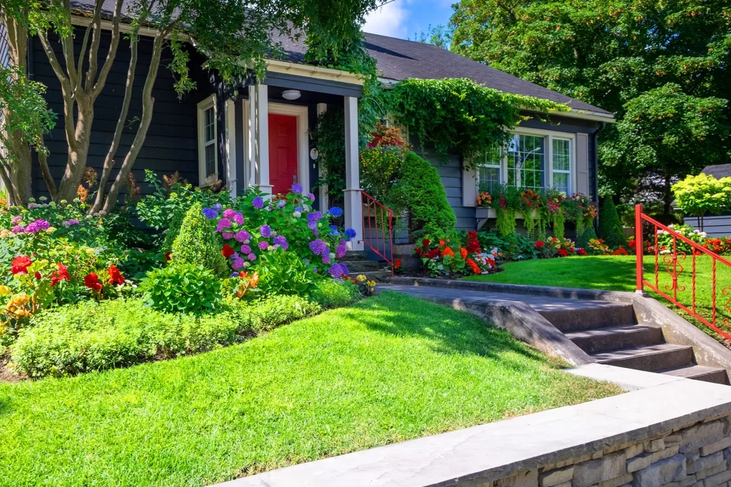 Cottage style home with lush landscaping and red front door