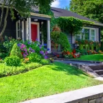 Cottage style home with lush landscaping and red front door