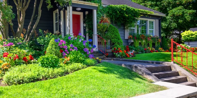 Cottage style home with lush landscaping and red front door