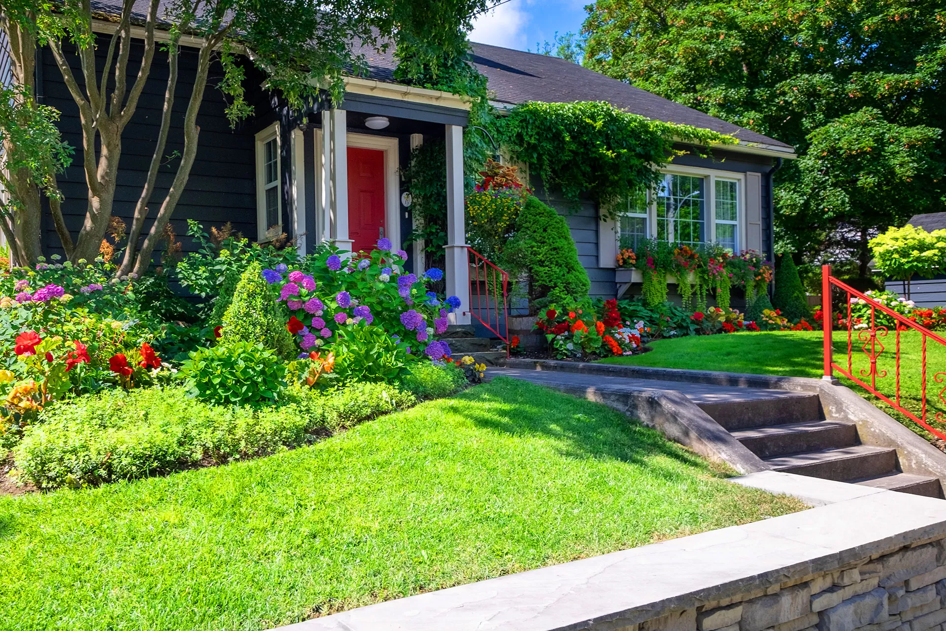 Cottage style home with lush landscaping and red front door